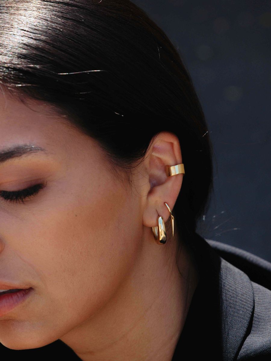 A woman wearing gold Wide Reversible Ear Cuff 
