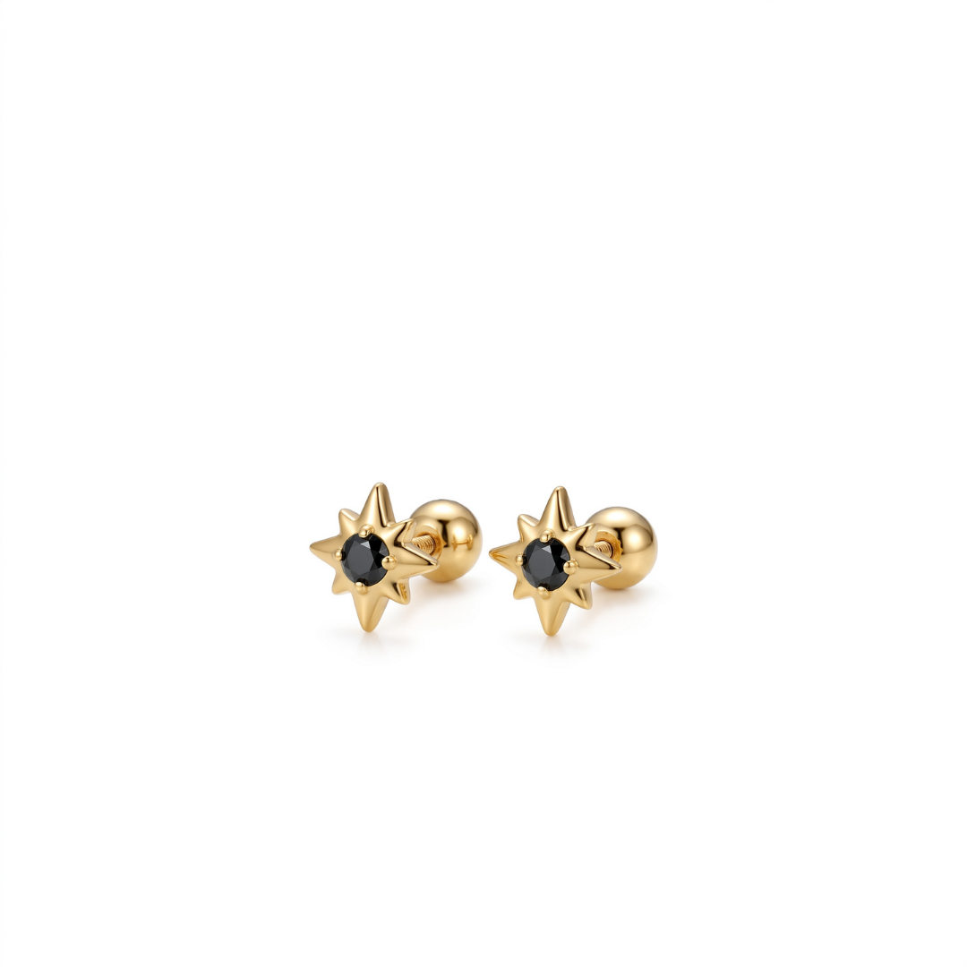 A pair of gold starburst stud earrings with a small round black gemstone in the center, set against a plain white background.