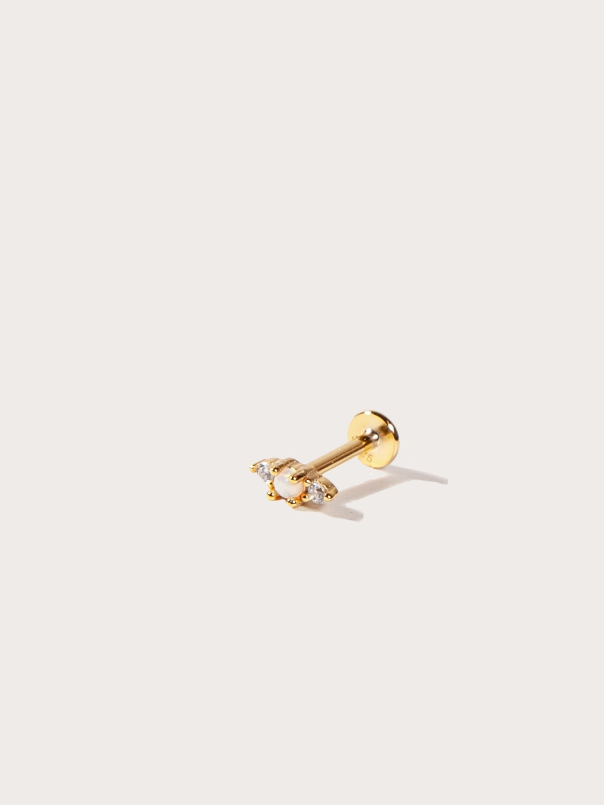 Gold flatback earring with a clear gemstone on a white background