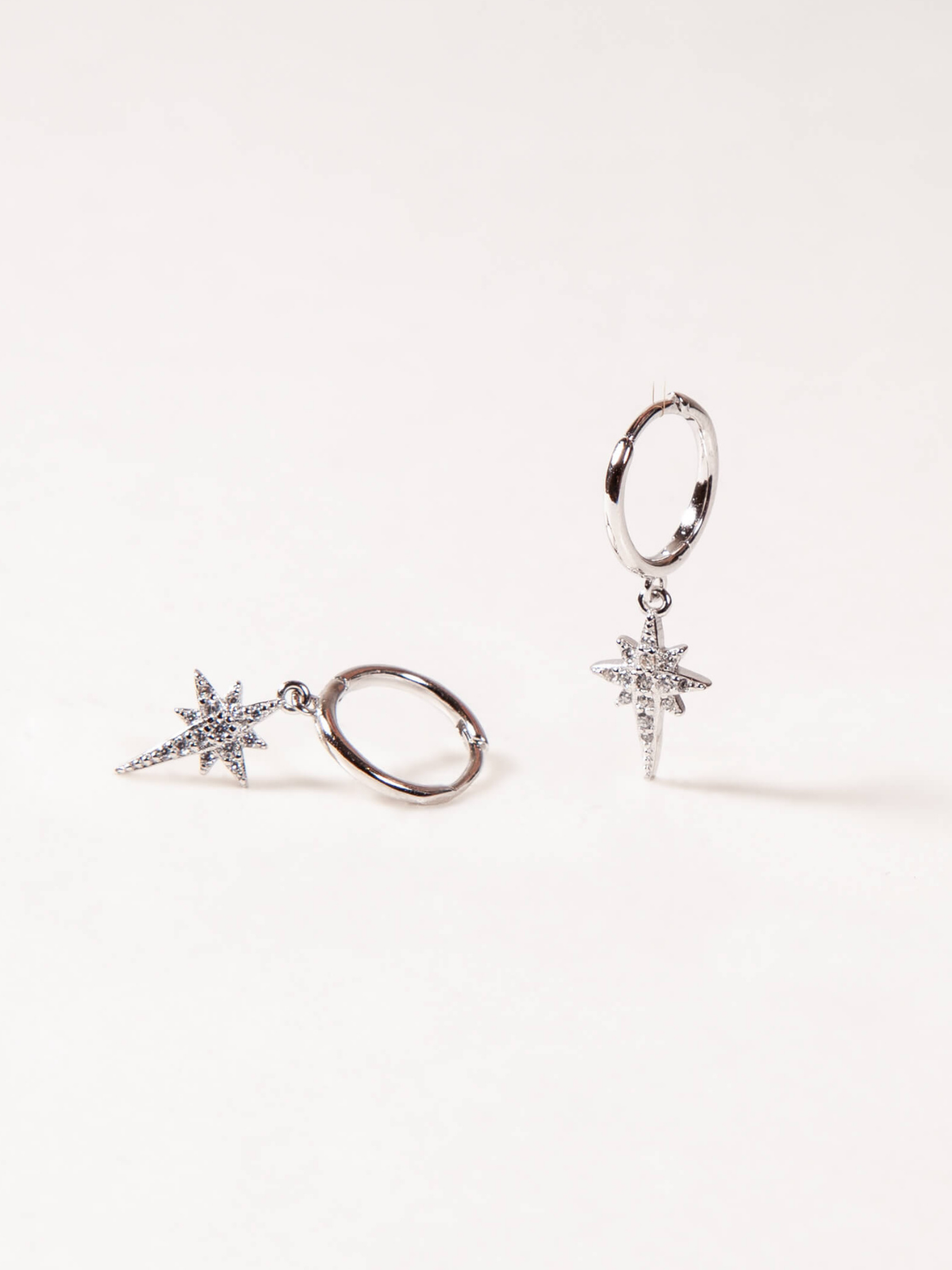 Pair of silver hoop earrings with star-shaped charms on a white background