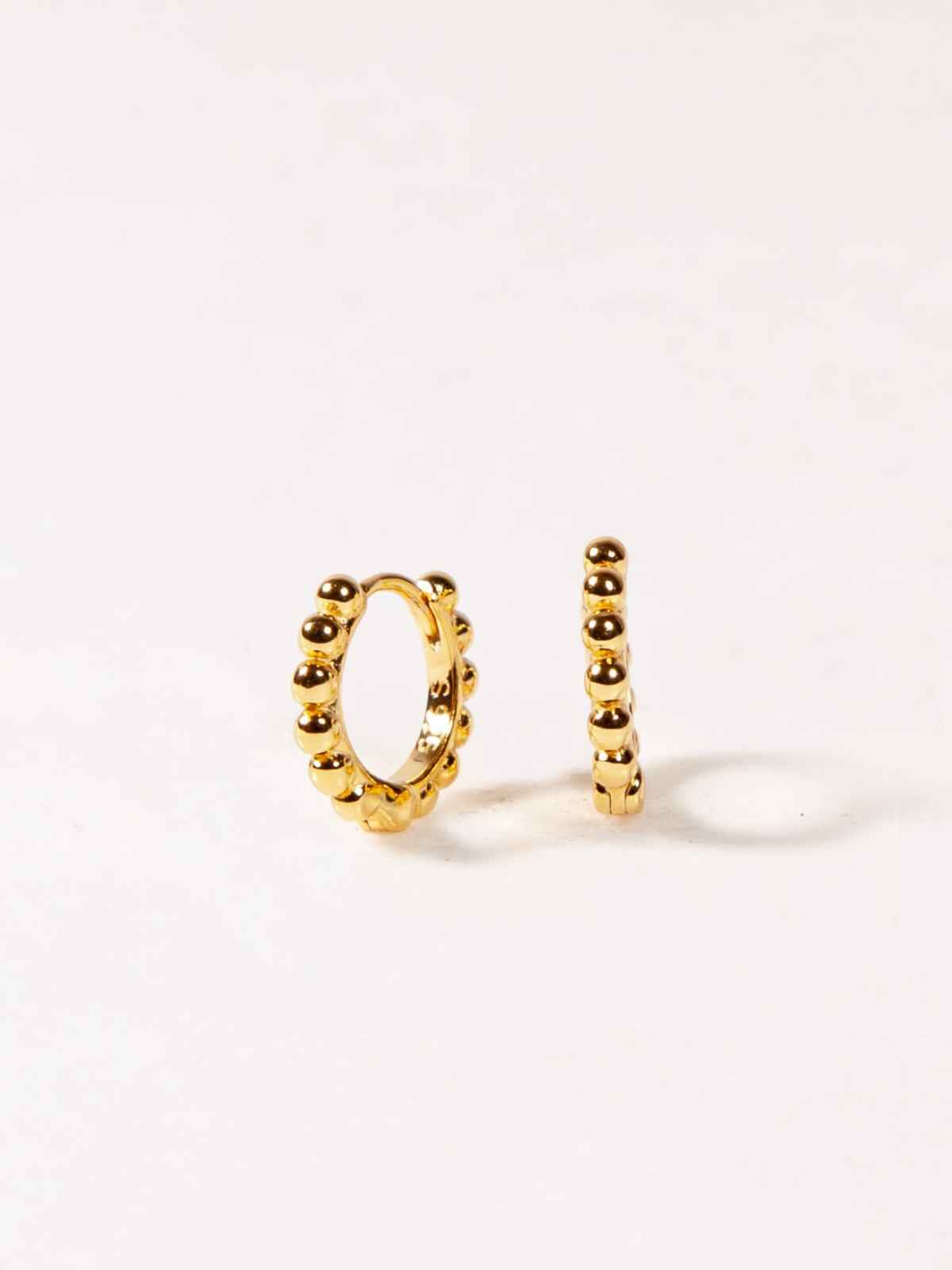 Gold hoop earrings with beads on a white background