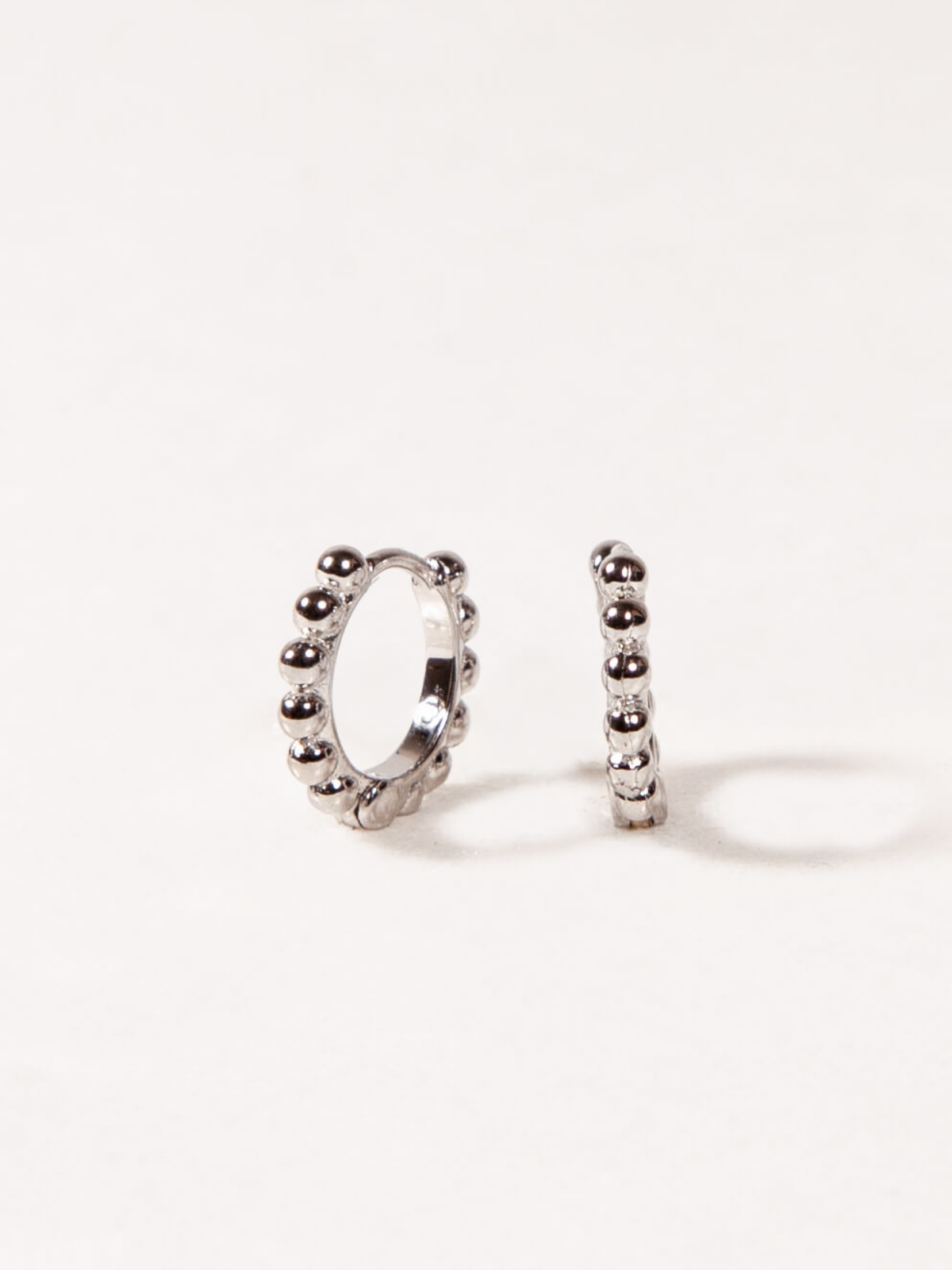 Pair of silver hoop earrings with bead details on a white background