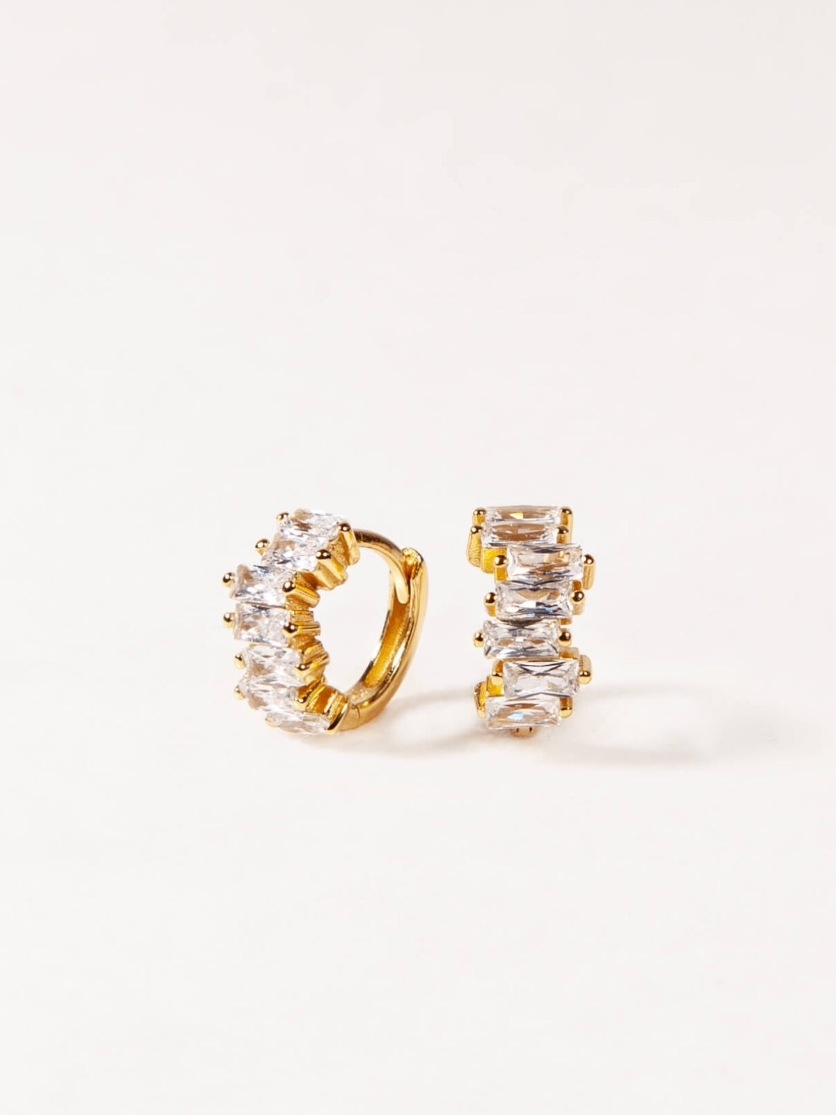 Gold hoop earrings with clear gemstones on a white background