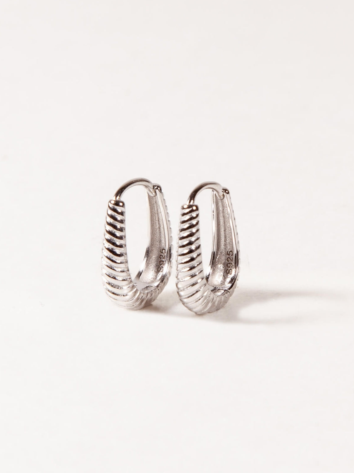 Pair of silver Oval hoop earrings on a white background