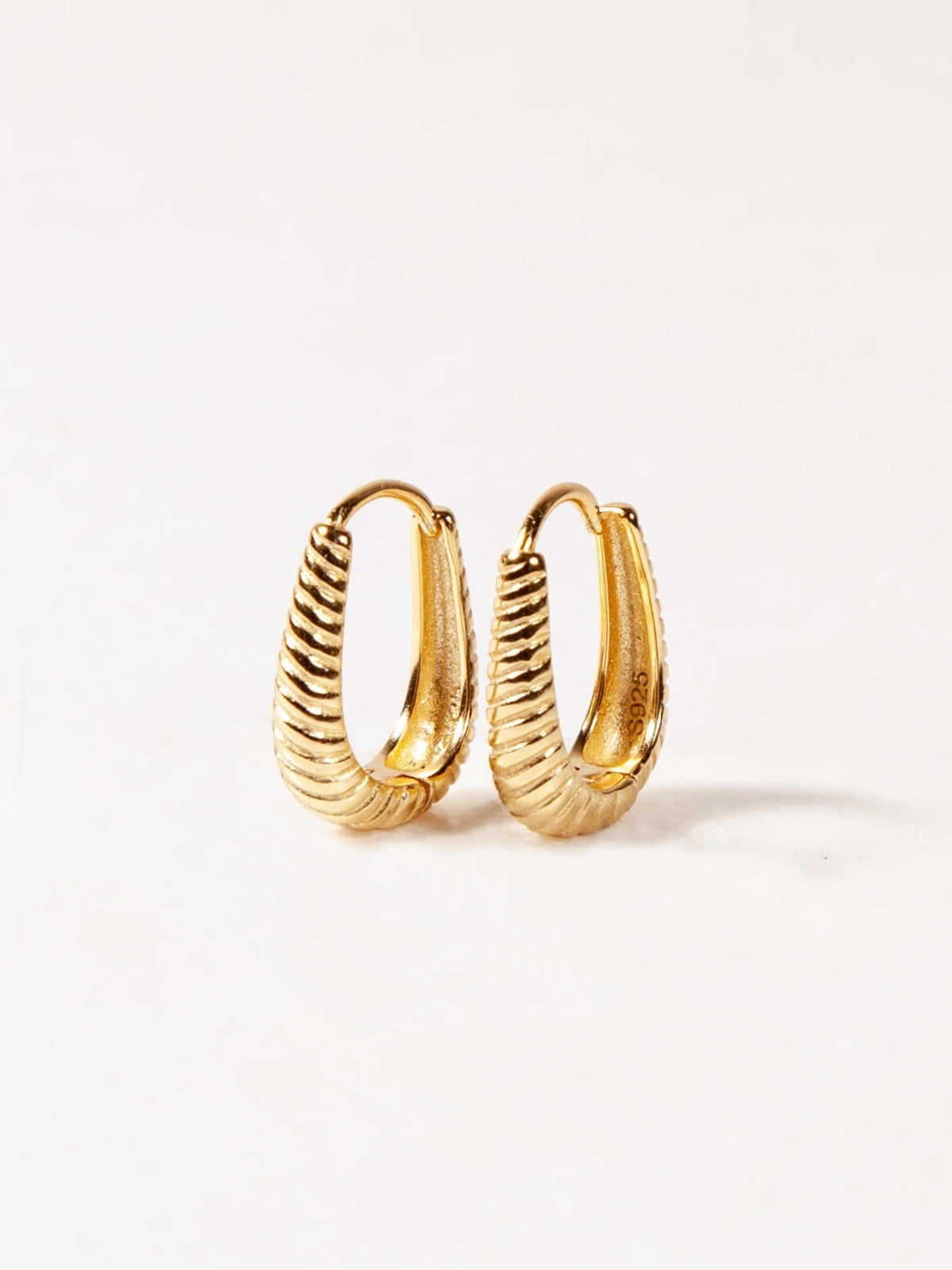 Pair of gold Oval hoop earrings on a white background