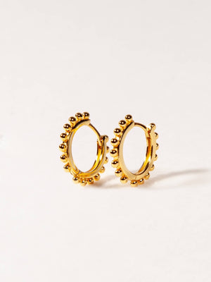 Gold hoop earrings with bead detailing on a light gray background