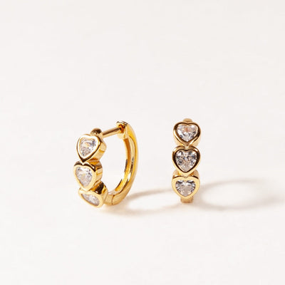Gold hoop earrings with heart-shaped gemstones on a white background