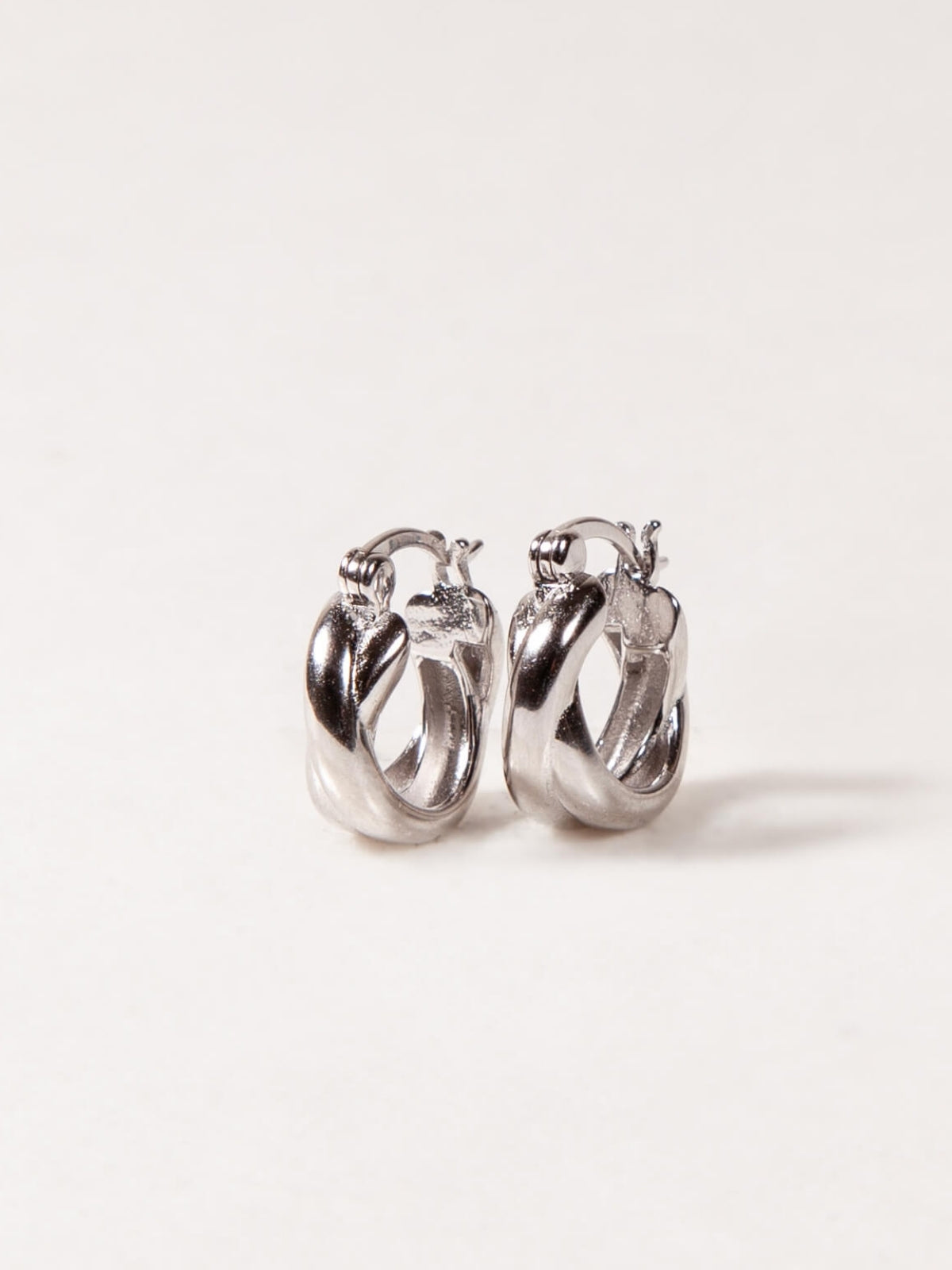 Pair of silver twisted hoop earrings on a light gray background