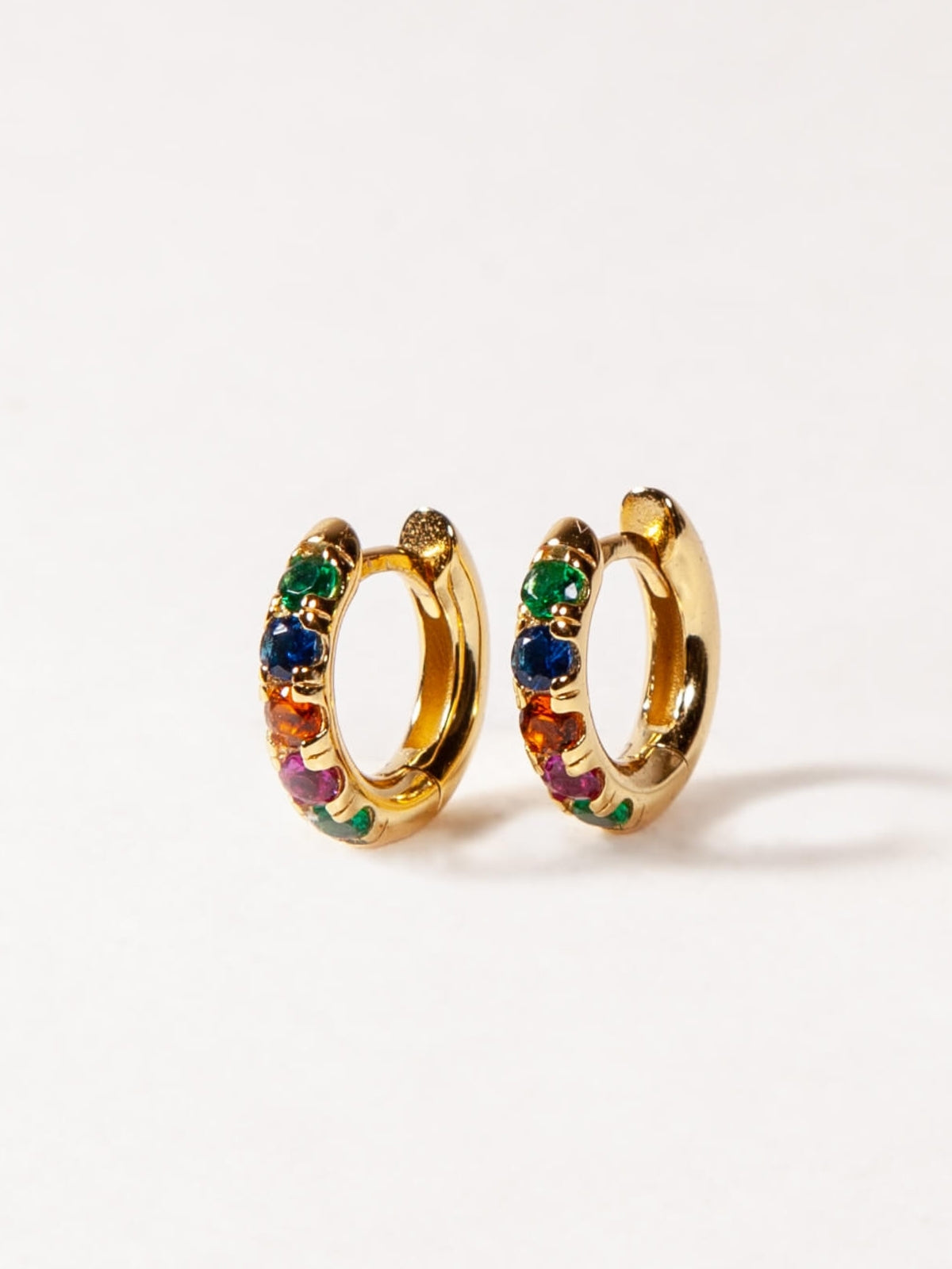 Gold hoop earrings with colorful gemstones on a white background