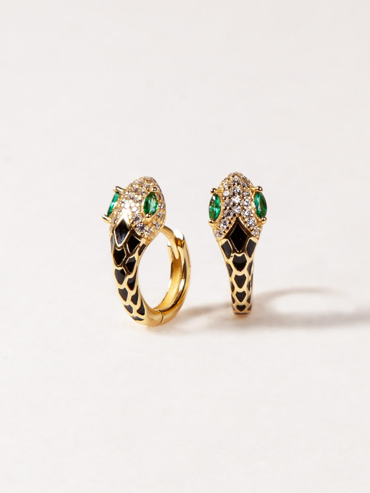 Pair of gold earrings with green gemstones on a white background