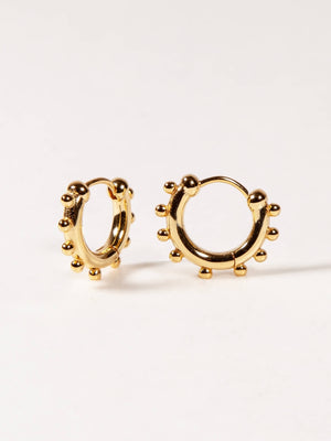Gold hoop earrings on a light beige background