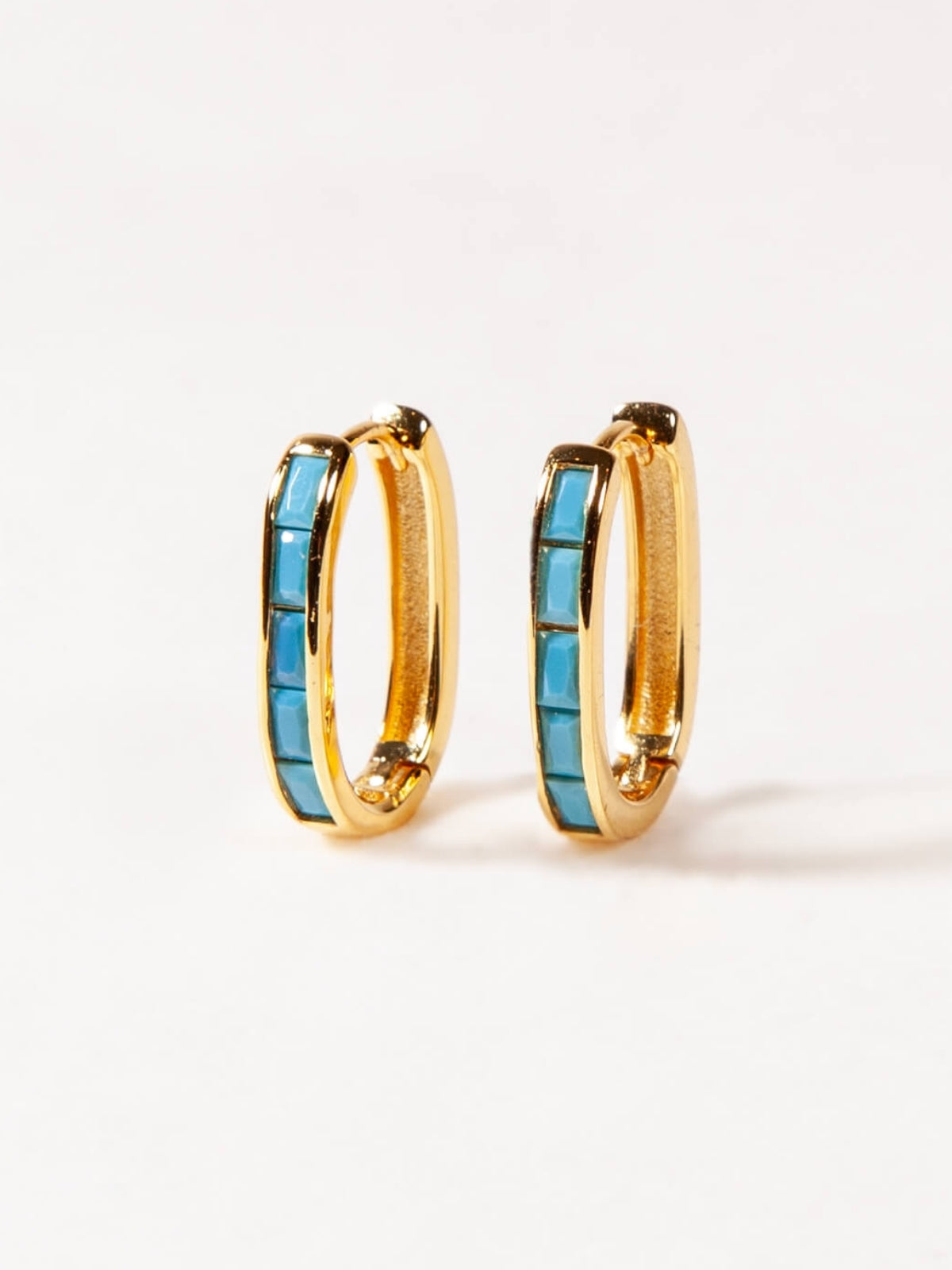Gold U shaped hoop earrings with turquoise stones on a white background