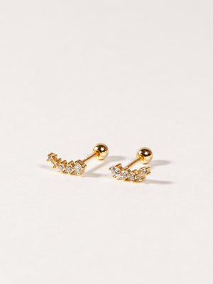 A pair of gold stud earrings with cubic zirconia stones, designed in a shooting star shape, displayed against a white background.