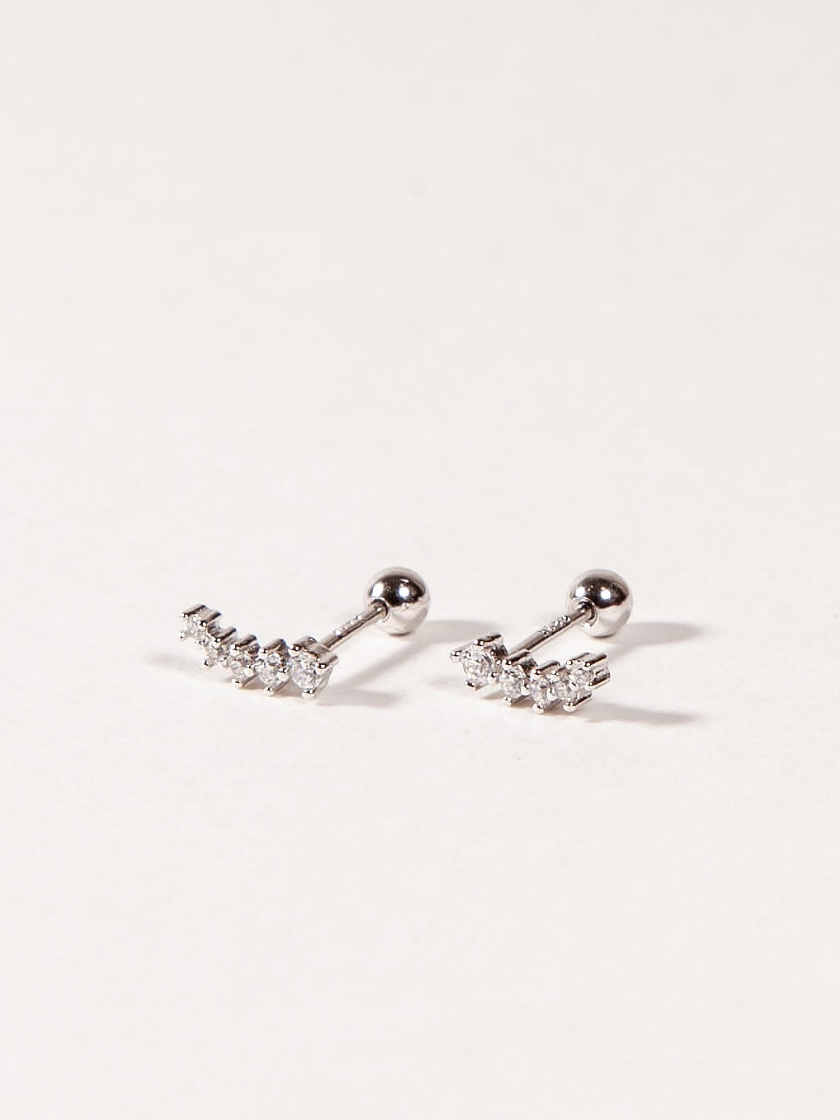 A pair of silver stud earrings with cubic zirconia stones, designed in a shooting star shape, displayed against a white background.
