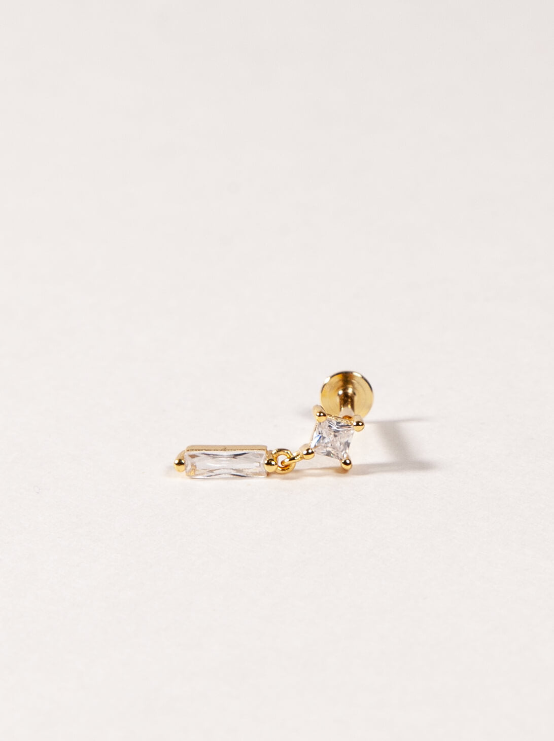 Gold earring with clear cz on a light beige background